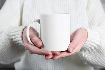 Woman holding blank white ceramic mug, closeup. Mockup for design