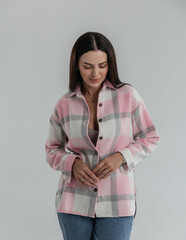 Portrait of a cute girl model in a pink checkered shirt and jeans in the studio on a white...