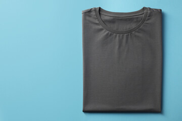 One blank t-shirt on light blue background, top view. Mockup for design