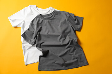 Blank t-shirts on yellow background, flat lay. Mockup for design