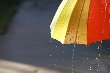 Open bright umbrella under pouring rain outdoors, closeup. Space for text