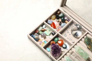 Box with beautiful gemstones on light table, closeup. Space for text