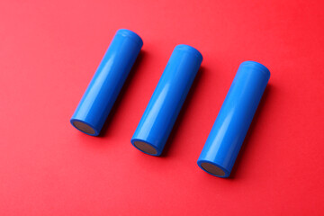 Three AA cell batteries on red background, closeup