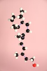 Molecule of retinol (vitamin A) on pink background. Chemical model