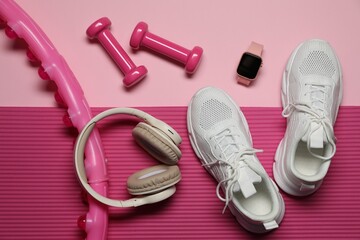 Dumbbells, watch and other fitness equipment on pink background, flat lay