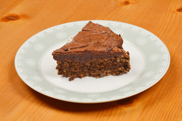 A side view of slice of homemade chocolate cake presented on a decorative plate