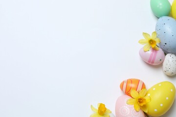 Happy Easter. Colorful eggs and yellow flowers on white background, space for text or advertising