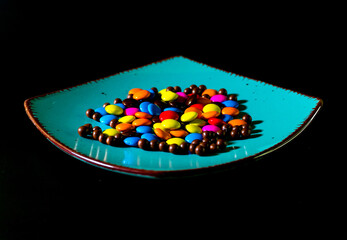Close-up of colorful chocolate candies on a vibrant turquoise plate, perfect for food and confectionery themes