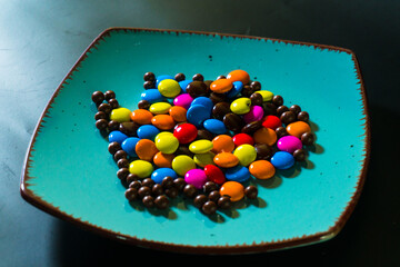 Close-up of colorful chocolate candies on a vibrant turquoise plate, perfect for food and confectionery themes