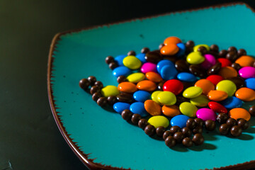 Close-up of colorful chocolate candies on a vibrant turquoise plate, perfect for food and confectionery themes