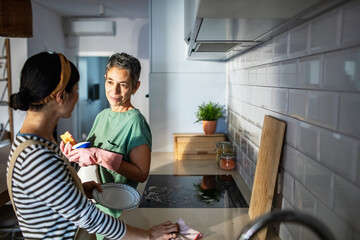 Lesbian couple washing kitchen countertop together