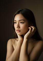 Obraz premium Thoughtful Asian Woman Touching Hair Contemplative Beauty and Self-Care