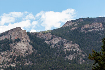 Majestic Mountain Landscape Under a Clear Blue Sky With Scattered Clouds and Lush Greenery