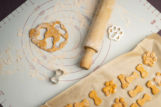 Making crunchy homemade baked healthy dog treat biscuits, dough made with sweet potato, applesauce, egg, whole wheat flour.