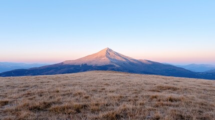Majestic mountain peak at sunset, golden grasslands, distant hills. Landscape photography for travel brochures