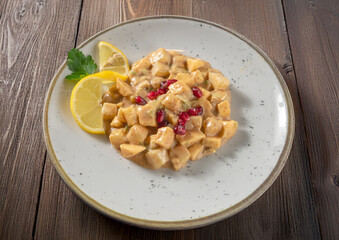 Aloo Chaat cold appetizer from traditional Indian cuisine with potatoes, pineapple, apples, mayonnaise, fresh tomato, sugar and spices seen up close and isolated on a woodwn backgraound background