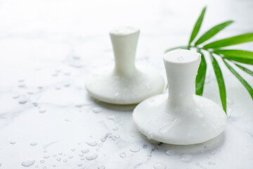 Wet spa stones and green palm leaf on white marble table, closeup. Space for text
