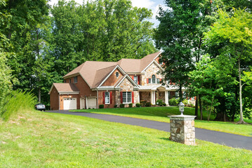Large modern single family country house with driveway.Blue sky with clouds.
