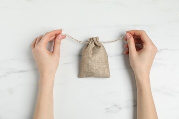 Woman with burlap bag at white marble table, top view