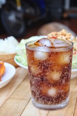 Cola soft drink with ice cubes and papaya salad spicy Thai food