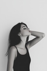 Fototapeta premium Arafed woman wearing a black top poses against a white background, thoughtfully resting her hand on her head, exuding a sense of contemplation.