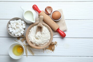 Rolling pin and ingredients for dough on white wooden table, flat lay. Space for text
