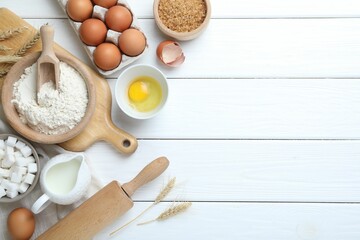 Rolling pin and ingredients for dough on white wooden table, flat lay. Space for text