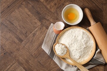 Rolling pin, flour and yolk on wooden table, flat lay. Space for text
