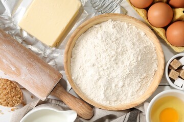Rolling pin and ingredients for dough on table, flat lay
