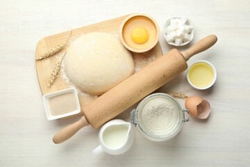 Rolling pin and different ingredients on light wooden table, flat lay