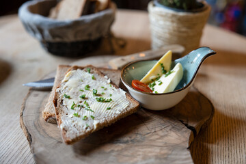 Traditionelles Butterbrot aus frischem Bauernbrot mit Fassbutter und Schnittlauch, rustikal serviert mit Käse und Tomate auf Holzbrett, bayerische Brotzeit

