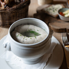 Traditionelle Münchner Weißwürste im Weißwursttopf mit frischen Schnittlauchringen, rustikales Wirtshausambiente mit Brezenkorb und bayerischer Gemütlichkeit

