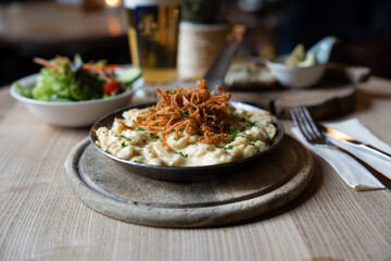 Deftige Käsespätzle mit Röstzwiebeln und Bier im Wirtshaus

