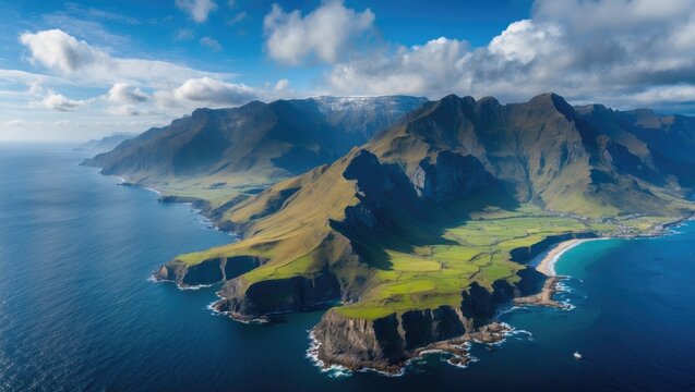 Aerial view of dramatic coastal cliffs and mountains surrounded by turquoise ocean and green landscape under a partly cloudy sky.