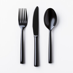 Black fork, knife, and spoon arranged neatly on white background, showcasing modern cutlery design. Perfect for dining settings or culinary presentations