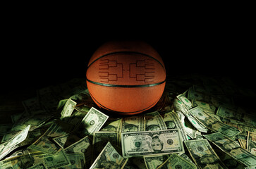 Basketball with march madness tournament bracket on a pile of cash
