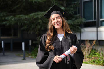 Happy graduating student holding diploma celebrating graduation day