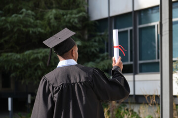Proud graduate standing outdoors holding his diploma after the graduation ceremony