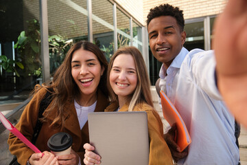 Happy multi ethnic students taking selfie outside university building