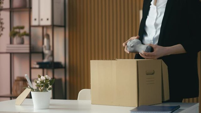 Woman packs her belongings in box, getting fired and preparing to leave her job