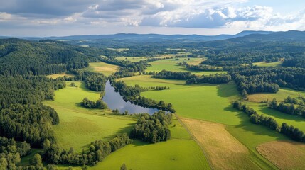 Obraz premium An aerial view showcases a serene river meandering through a vibrant green valley, surrounded by lush vegetation and natural beauty.