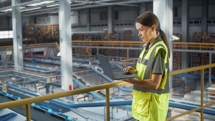 Sortation Fullfilment Center: Female Supervisor Associate USes Laptop. Logistics, Transportation Warehouse Facility with Conveyor Loading Boxes for Online Shoppping Order Delivery to Customers