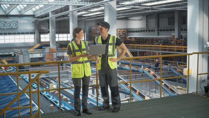 Caucasian Female Ecommerse Businesswoman Talking To Male Logistics Director In Warehouse Facility With Automated Conveyor Belt. Man And Woman Working On Packaging And Delivering Products To Clients.