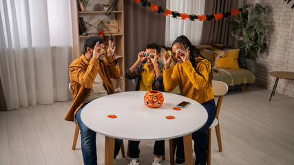 African american family of mom, dad and little son preparing for halloween celebrations, sitting at...