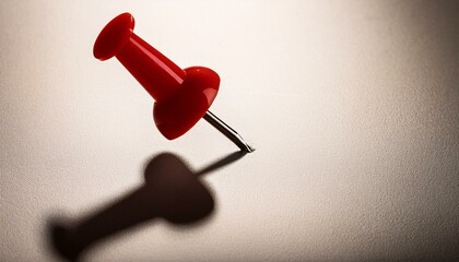A red push pin casting a shadow.