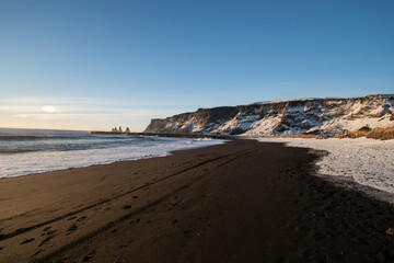 Landscape with snow covered mountains and black sand beach in Reynisfjara, Iceland