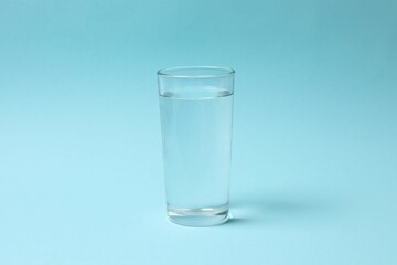 Transparent glass with water on blue background. Drinking clear water in the morning for health