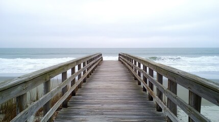 Obraz premium A wooden pier on a peaceful beach, stretching towards the horizon as waves crash gently against the posts.