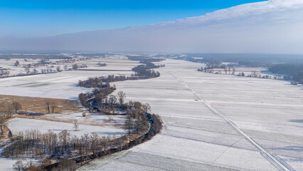 meanders of the prosny river in fields and meadows on a winter day. river bends, beautiful nature. snow on the fields. beautiful blue sky with an approaching snow wave.