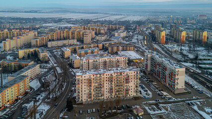 Fototapeta premium winter city landscape aerial view from drone. snowy city in the morning during sunrise. residential buildings, apartment blocks. panorama of the large city of Kalisz